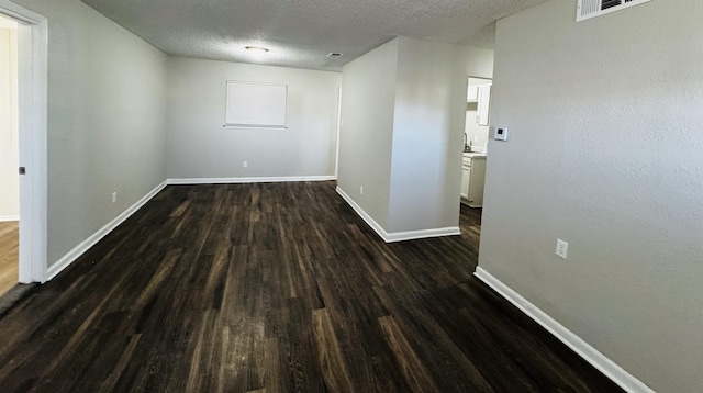 spare room with a textured ceiling, dark hardwood / wood-style floors, and sink