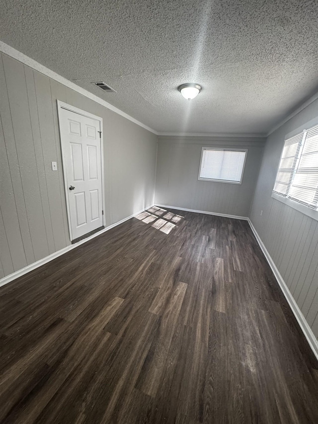 spare room featuring a textured ceiling, dark hardwood / wood-style flooring, and crown molding