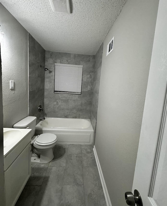 full bathroom with a textured ceiling, vanity, tiled shower / bath combo, and toilet