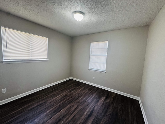 empty room with dark hardwood / wood-style flooring and a textured ceiling