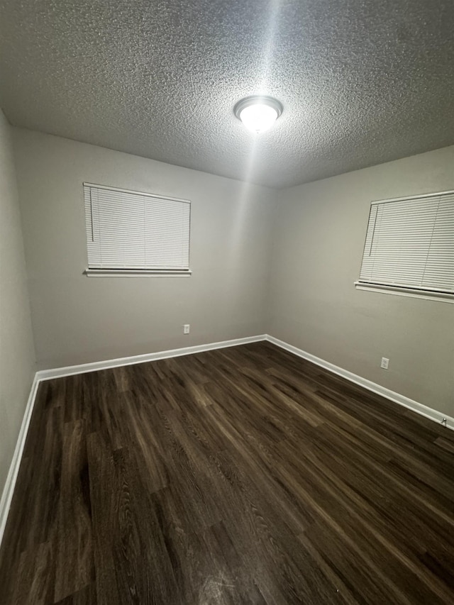 empty room featuring a textured ceiling and dark wood-type flooring