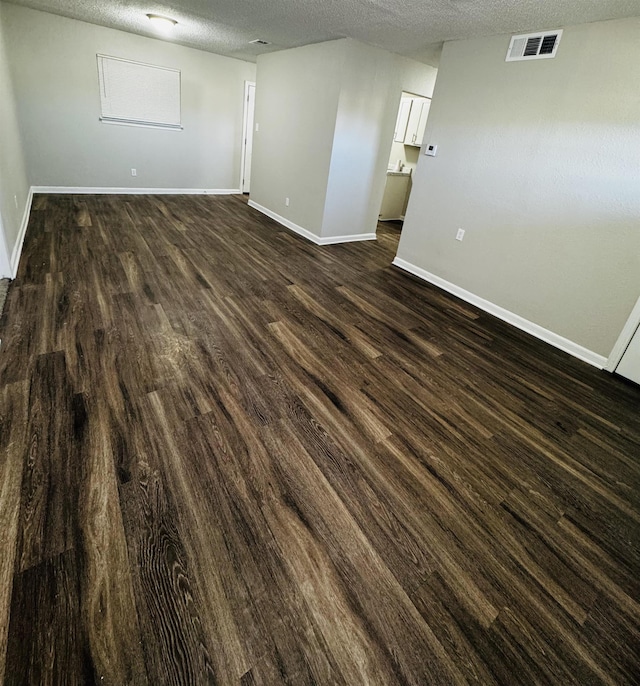 unfurnished room with a textured ceiling and dark wood-type flooring