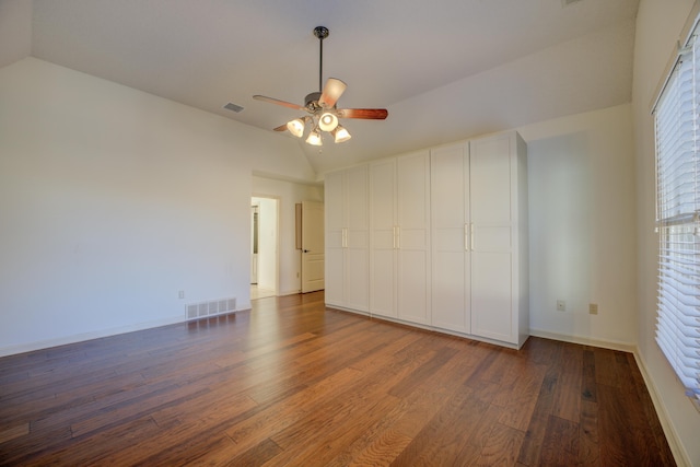 unfurnished bedroom with dark hardwood / wood-style flooring, vaulted ceiling, and ceiling fan