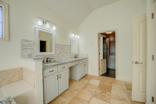 bathroom with tasteful backsplash, a tub, vanity, and vaulted ceiling