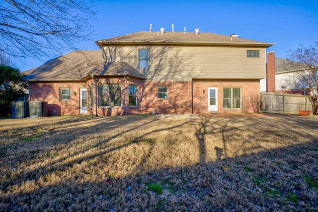 back of property with central AC unit and a lawn