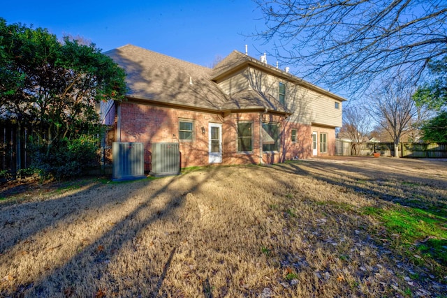 rear view of property featuring a yard and central air condition unit