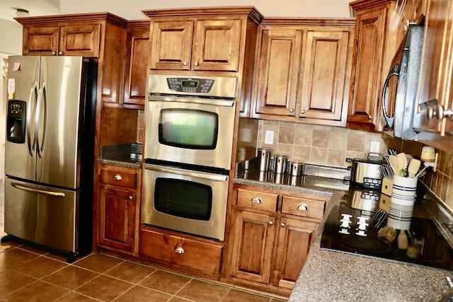 kitchen with decorative backsplash, stainless steel appliances, and dark tile patterned floors