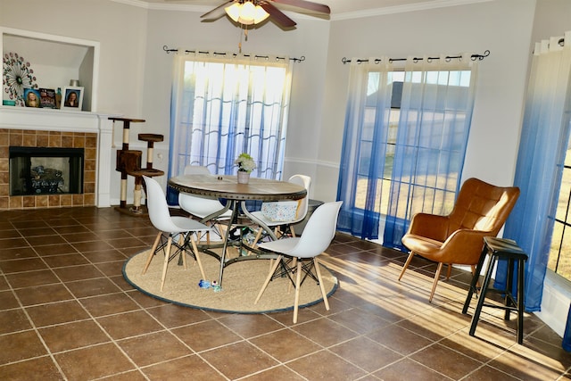 tiled dining area featuring crown molding, a fireplace, and ceiling fan