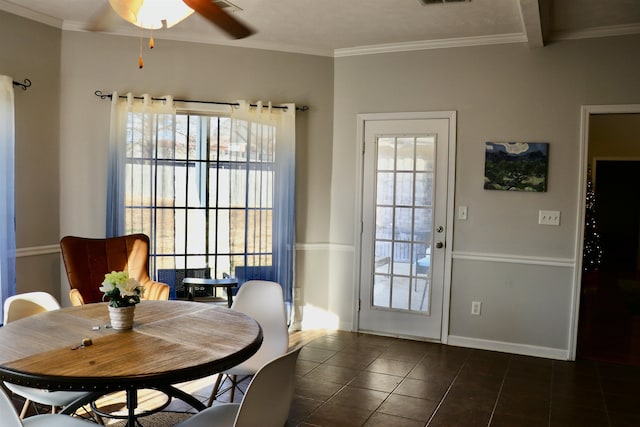 dining area with dark tile patterned floors, plenty of natural light, crown molding, and ceiling fan