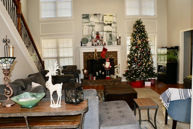 living room featuring a high ceiling, a brick fireplace, and hardwood / wood-style floors