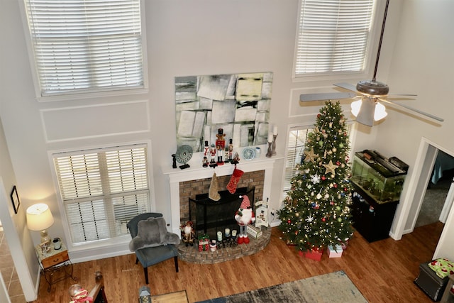 living room with a wealth of natural light, hardwood / wood-style floors, ceiling fan, and a brick fireplace