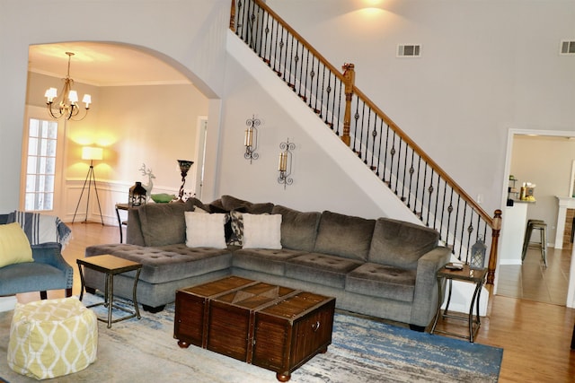 living room featuring a fireplace, hardwood / wood-style floors, an inviting chandelier, and ornamental molding