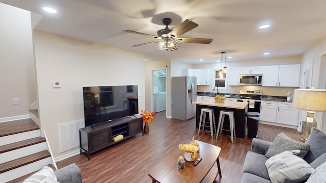 living room with ceiling fan, sink, dark wood-type flooring, and washer / dryer