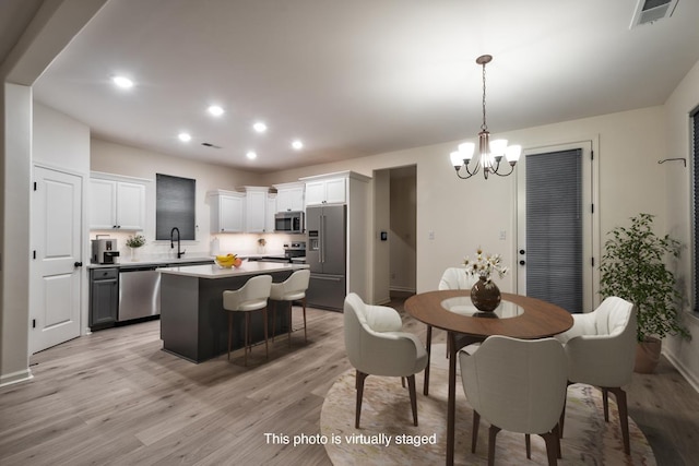 dining room featuring sink, light hardwood / wood-style floors, and a notable chandelier