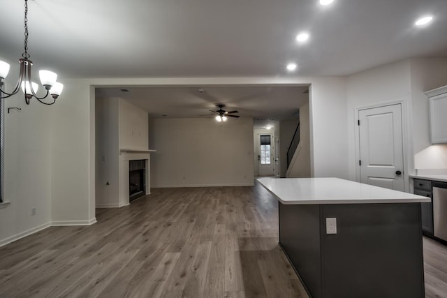 kitchen with wood-type flooring, a center island, decorative light fixtures, and a tiled fireplace