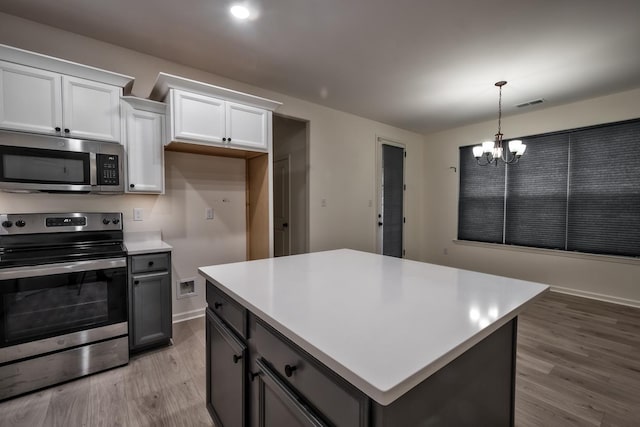 kitchen with white cabinets, a chandelier, light wood-type flooring, and appliances with stainless steel finishes