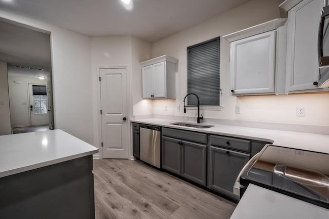 kitchen featuring stove, stainless steel dishwasher, sink, light hardwood / wood-style flooring, and gray cabinets