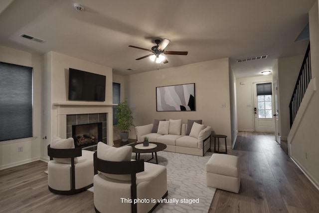 living room featuring ceiling fan, wood-type flooring, and a tile fireplace