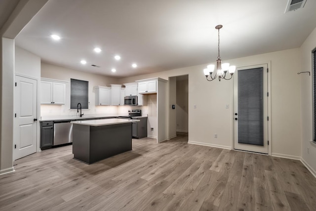 kitchen featuring a center island, stainless steel appliances, light hardwood / wood-style floors, decorative light fixtures, and white cabinets