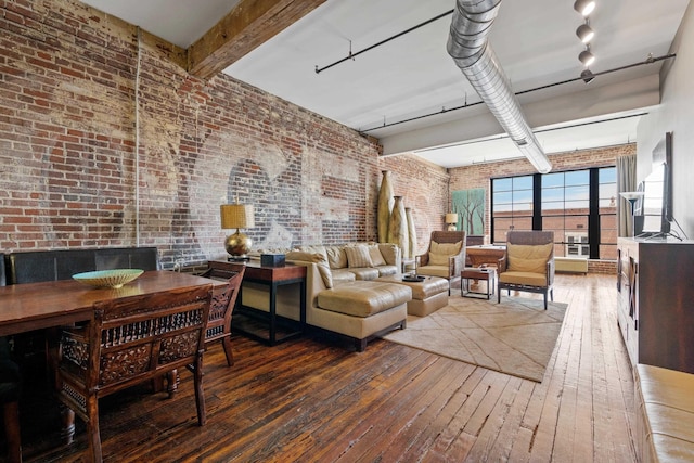 interior space with wood-type flooring, rail lighting, beam ceiling, and brick wall