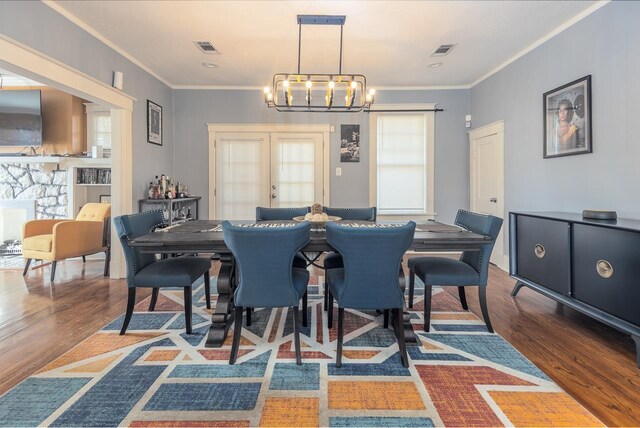 dining area with a chandelier, wood-type flooring, and ornamental molding