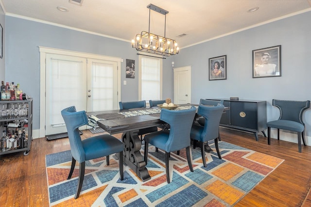 dining space featuring a chandelier, ornamental molding, french doors, and dark wood-type flooring