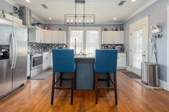 kitchen featuring white cabinets, plenty of natural light, wood-type flooring, and stainless steel appliances