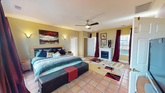 tiled bedroom featuring a fireplace and ceiling fan