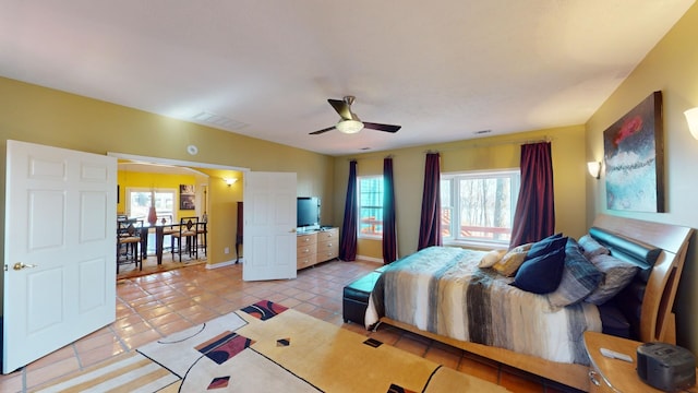 tiled bedroom featuring multiple windows and ceiling fan