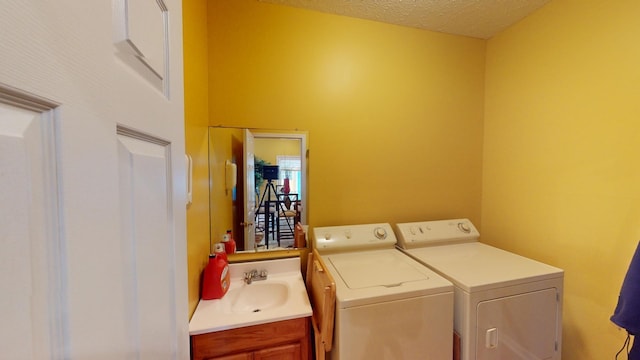 clothes washing area featuring washing machine and clothes dryer, a textured ceiling, and sink