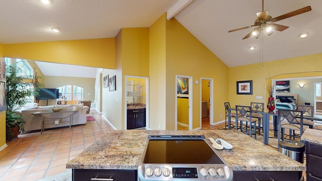 kitchen with ceiling fan, a center island, light stone counters, high vaulted ceiling, and range