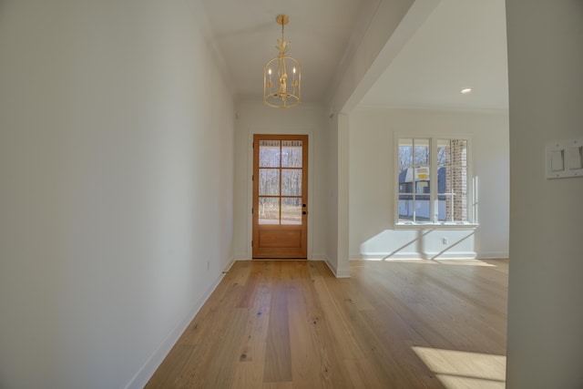 entryway featuring an inviting chandelier, light hardwood / wood-style flooring, plenty of natural light, and crown molding