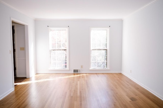 spare room featuring crown molding and light hardwood / wood-style floors