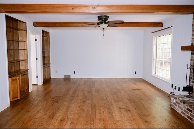 unfurnished living room with hardwood / wood-style flooring, ceiling fan, beam ceiling, and a fireplace