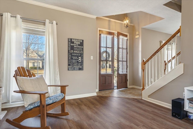 foyer entrance with a textured ceiling, crown molding, dark wood-type flooring, and an inviting chandelier