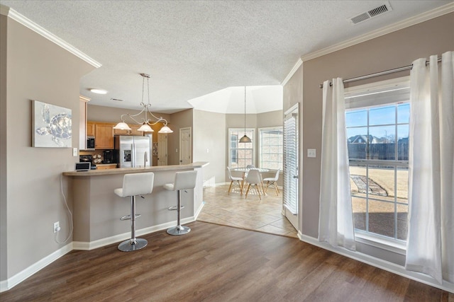 kitchen featuring hardwood / wood-style flooring, kitchen peninsula, a breakfast bar area, and appliances with stainless steel finishes