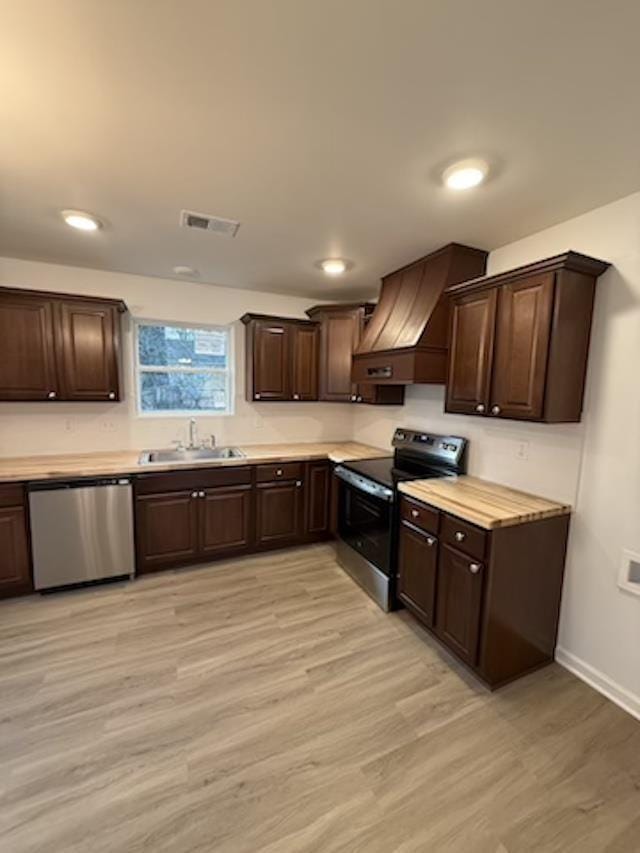 kitchen with sink, stainless steel appliances, dark brown cabinets, and light wood-type flooring