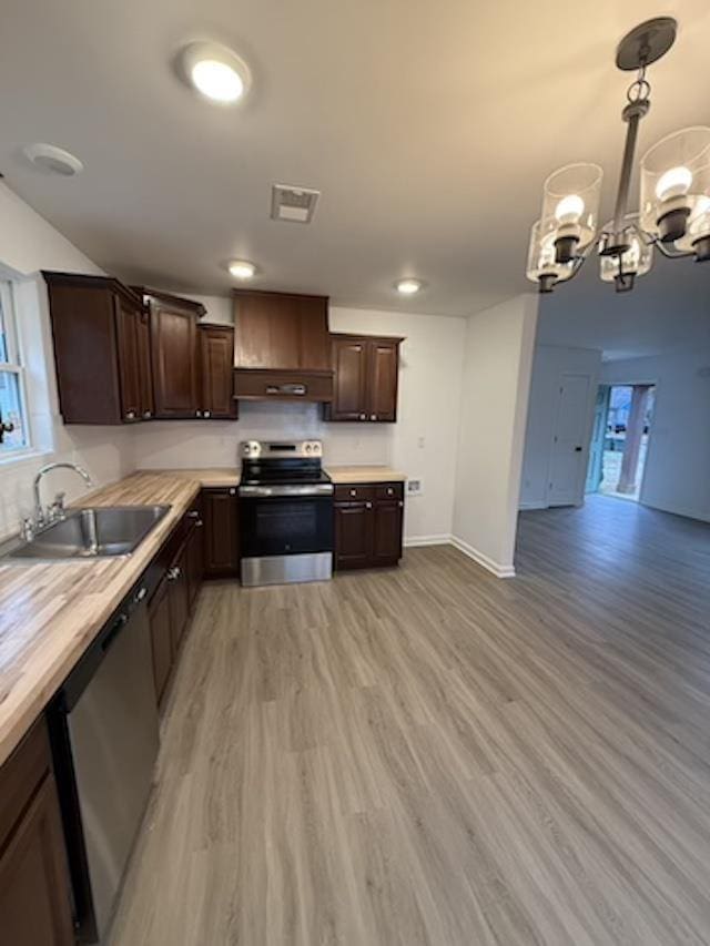 kitchen with sink, hanging light fixtures, a notable chandelier, butcher block countertops, and appliances with stainless steel finishes