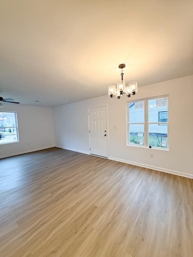 interior space featuring ceiling fan with notable chandelier and light wood-type flooring