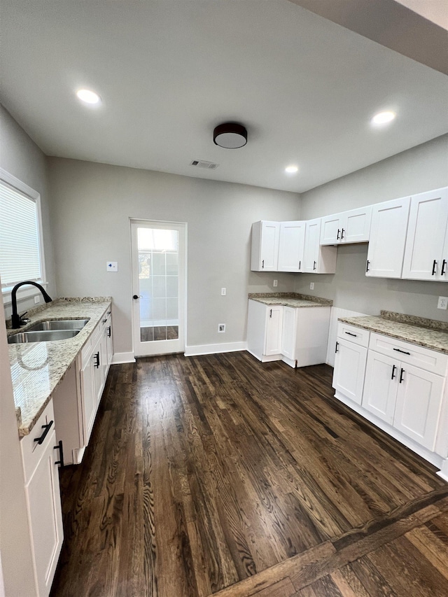 kitchen featuring white cabinets, light stone counters, dark hardwood / wood-style flooring, and sink