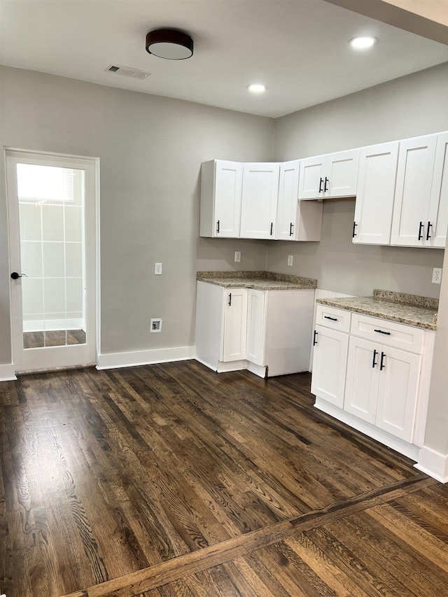 kitchen featuring white cabinets, dark hardwood / wood-style flooring, and light stone countertops