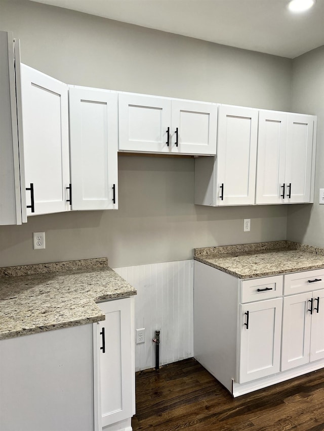 kitchen with white cabinets, dark hardwood / wood-style flooring, and light stone counters