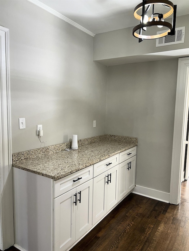 kitchen featuring white cabinetry, hanging light fixtures, light stone counters, and dark hardwood / wood-style floors