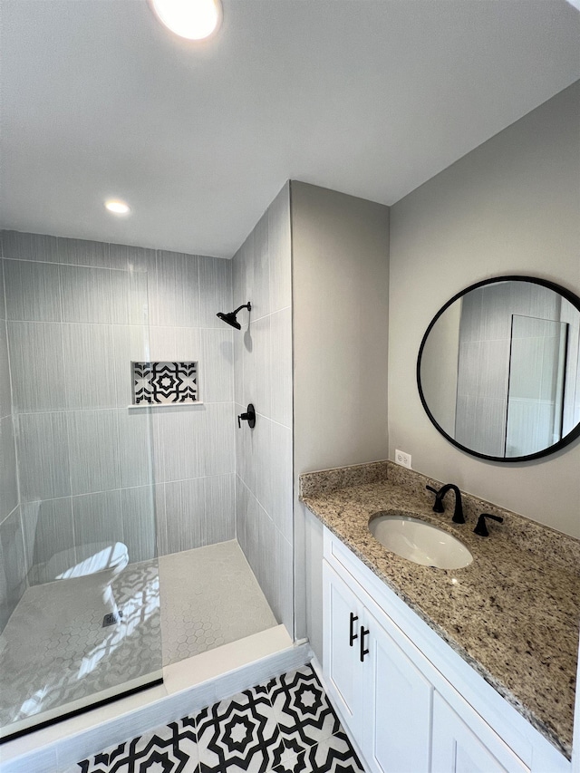 bathroom with a tile shower, tile patterned flooring, and vanity