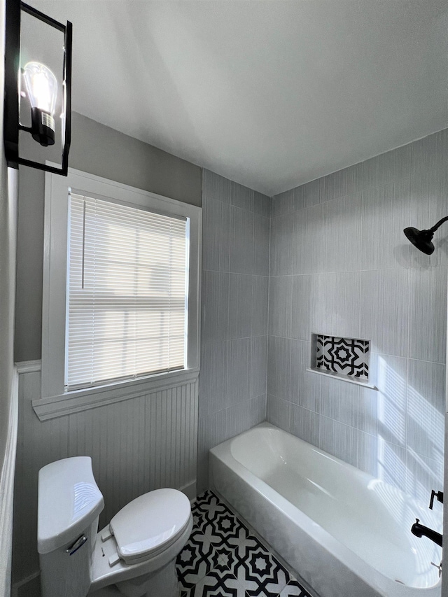 bathroom featuring tile patterned flooring, toilet, and tub / shower combination