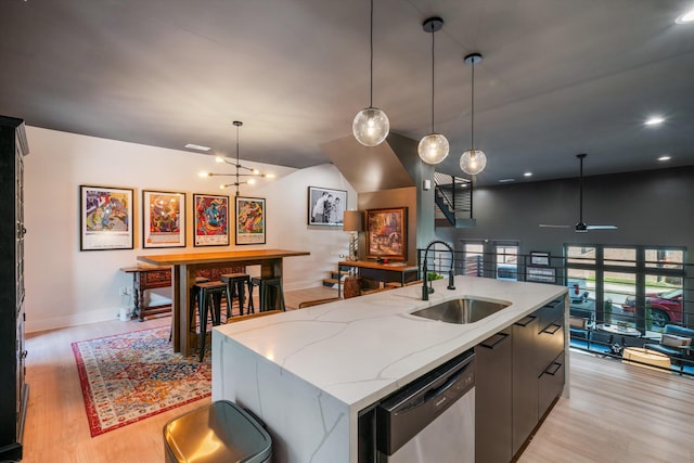 kitchen featuring dishwasher, sink, a kitchen island with sink, and light hardwood / wood-style flooring