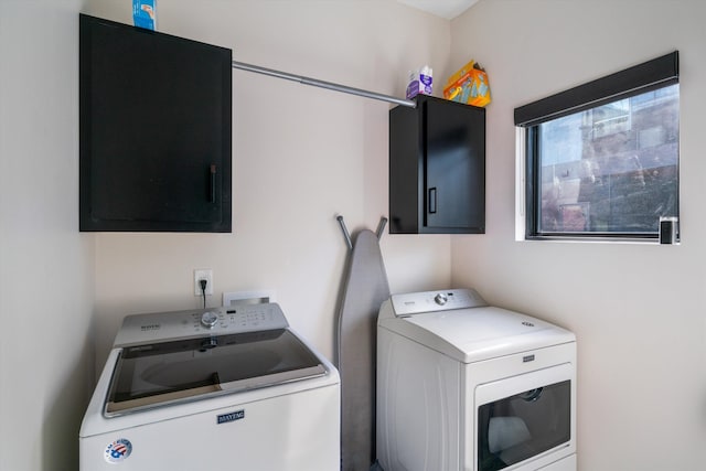 washroom featuring cabinets and washer and clothes dryer