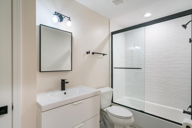 full bathroom featuring vanity, toilet, and bath / shower combo with glass door