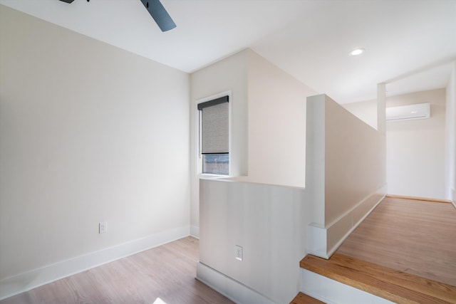 hall with light wood-type flooring and an AC wall unit