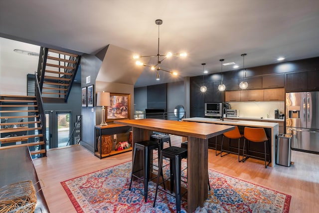 kitchen with light hardwood / wood-style floors, stainless steel refrigerator with ice dispenser, and a breakfast bar area